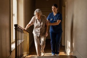 Oudere vrouw loopt voorzichtig trap af met fysiotherapeut na knieprothese voor stabiliteitstraining