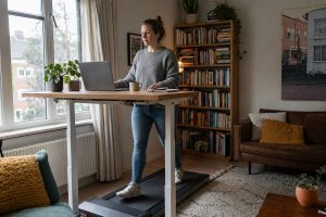 Vrouw loopt op walking pad onder staand bureau tijdens thuiswerken