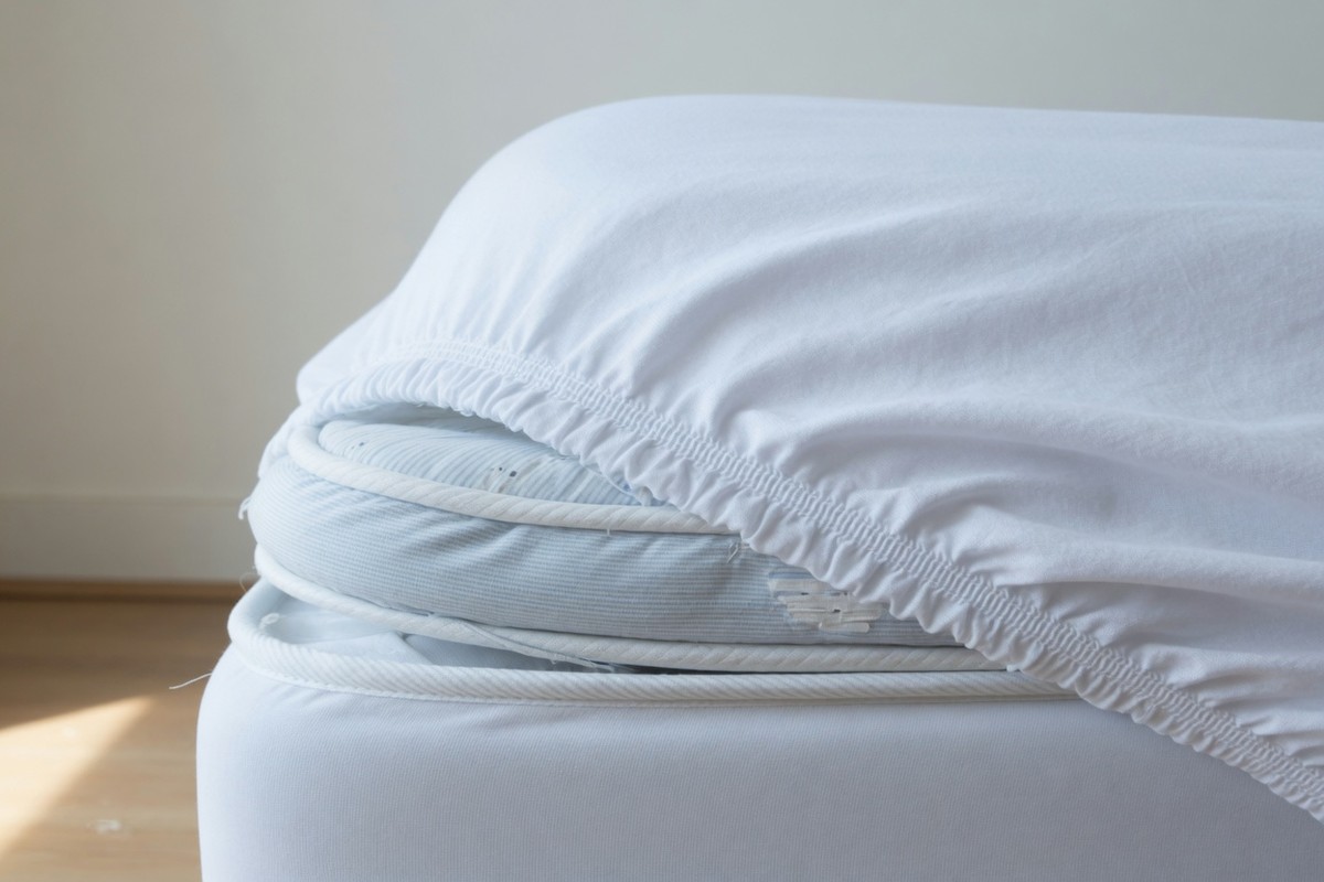 Wit hoeslaken over de hoek van een matras, elastiek zichtbaar