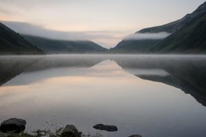 Stille bergmeer weerspiegelt lege hemel bij dageraad